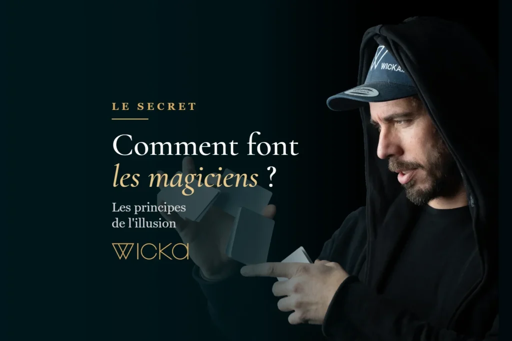 Wicka, capuche sur la tête, manipule des cartes dans la pénombre