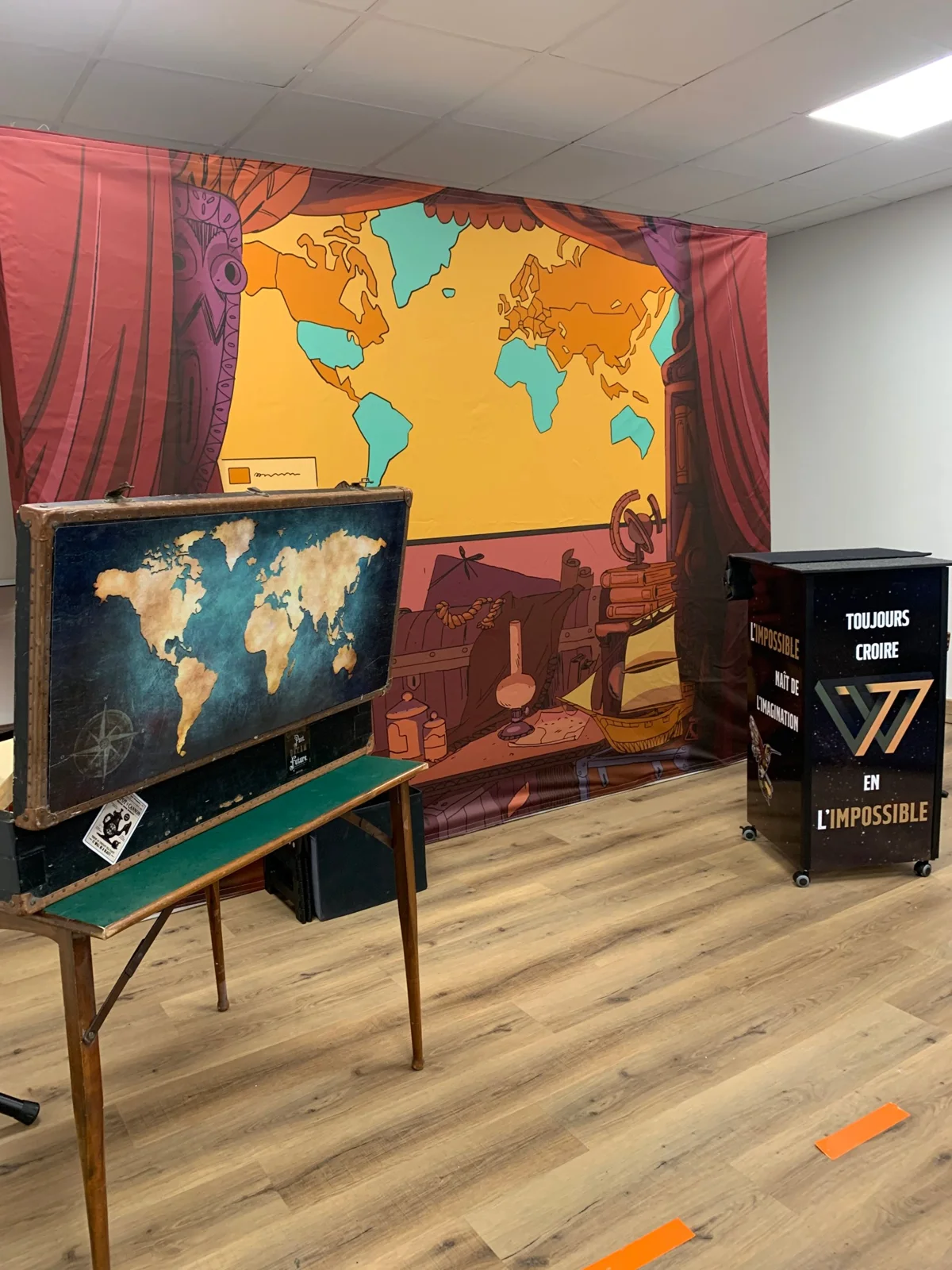 Décor du spectacle Chercheur d'Impossible : toile carte du monde, malle de voyage et pupitre Toujours croire en l'impossible